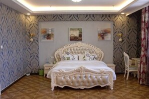 A bedroom with a large bed, a nightstand, a chair, and a wall with patterned wallpaper.