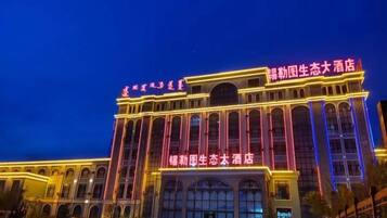 Un hotel grande con varios pisos, ventanas arqueadas y señalización iluminada.