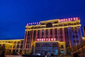 A large hotel with multiple stories, arched windows, and illuminated signage.