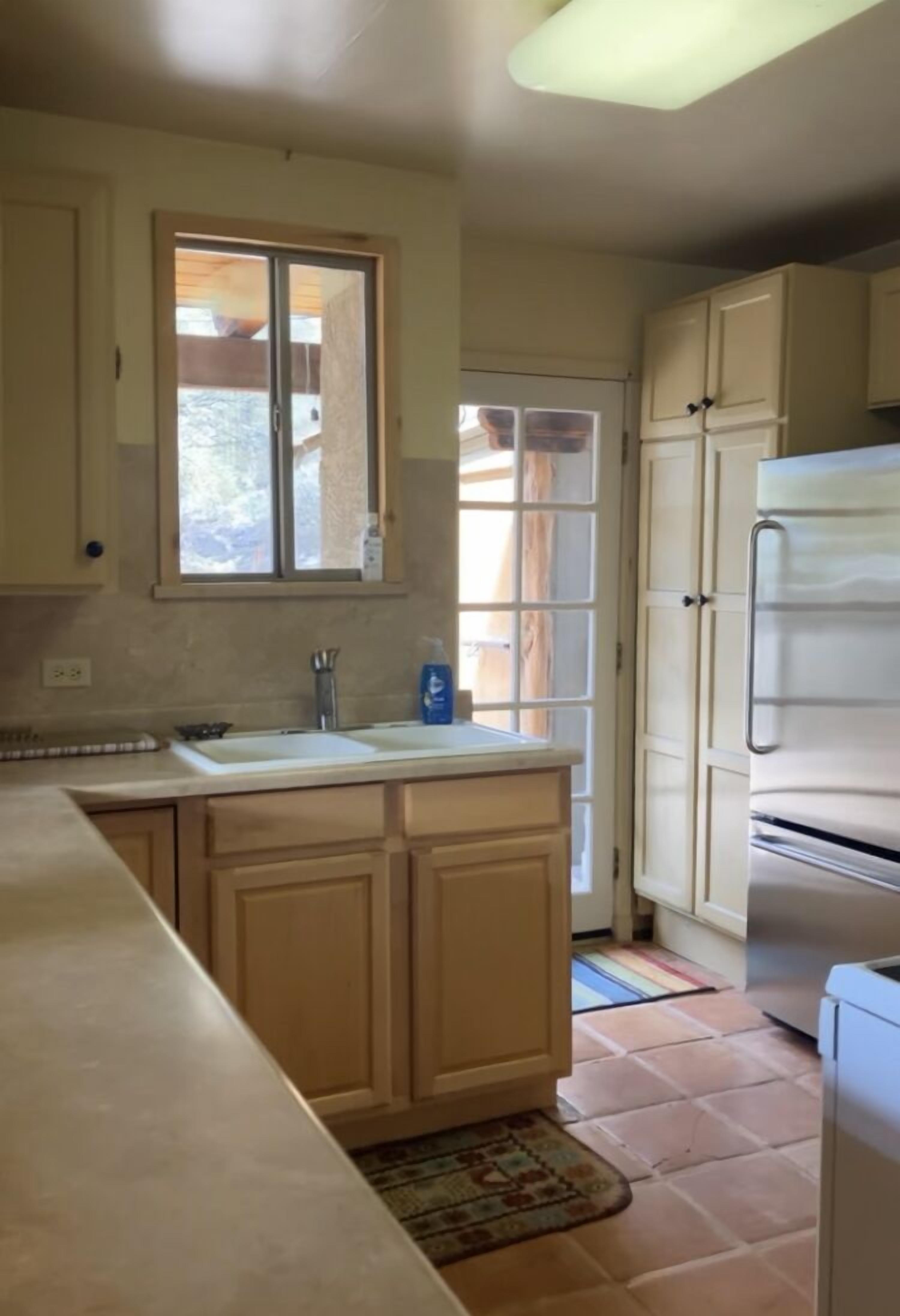 A kitchen with a large island, a double sink, and a refrigerator.
