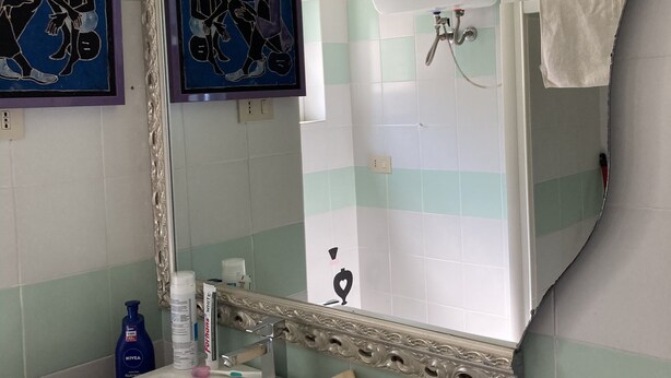 Ein Badezimmer mit einem großen Spiegel, einem Waschbecken mit Armatur und einer Duschkabine.