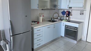 Eine kompakte Küche mit einem Edelstahl-Kühlschrank, einer Spüle und einem eingebauten Backofen.
