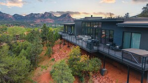 A modern building with a deck overlooking a mountainous landscape.