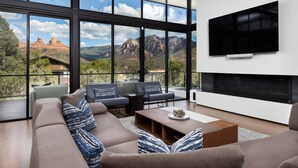 A modern living room with a large window, a flat-screen TV, and a fireplace.