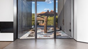 A modern interior with a sliding glass door leading to a patio area with a rock garden and a view of red rock formations.