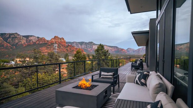 A balcony with a fire pit, outdoor seating, and a view of red rock formations.