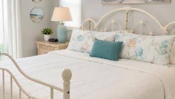 Una camera da letto con un letto, un comodino, una lampada e un quadro raffigurante una spiaggia.