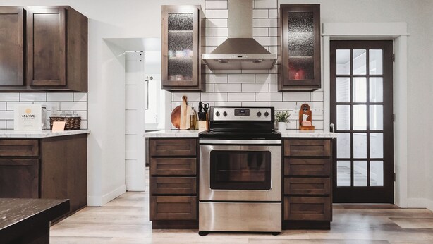 A kitchen with dark wooden cabinets, a stainless steel oven, and a white tiled backsplash. - Family & dog friendly; 5 min walk to beach, bars, downtown, restaurants and park (Detroit Lakes)
