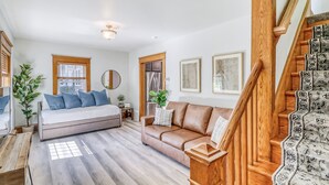 A modern living room with a sofa, a bed, a wooden staircase, and a dining area. - Family & dog friendly; 5 min walk to beach, bars, downtown, restaurants and park (Detroit Lakes)