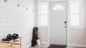A room with white wooden walls, a white door, and a window with a view. There is a shelf with shoes and a bag hanging on the wall. - Family & dog friendly; 5 min walk to beach, bars, downtown, restaurants and park (Detroit Lakes)
