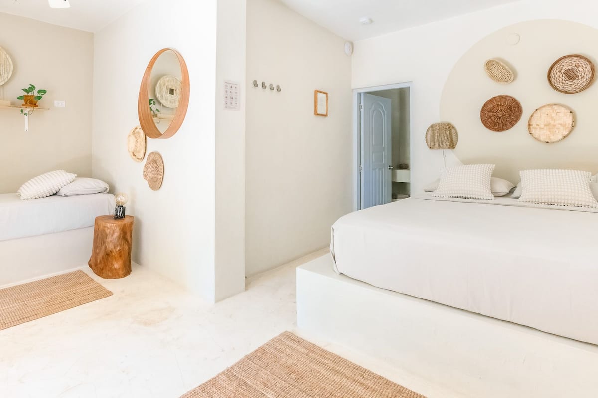 A modern bedroom with a large bed, a bedside table, a mirror, and wall-mounted baskets.
