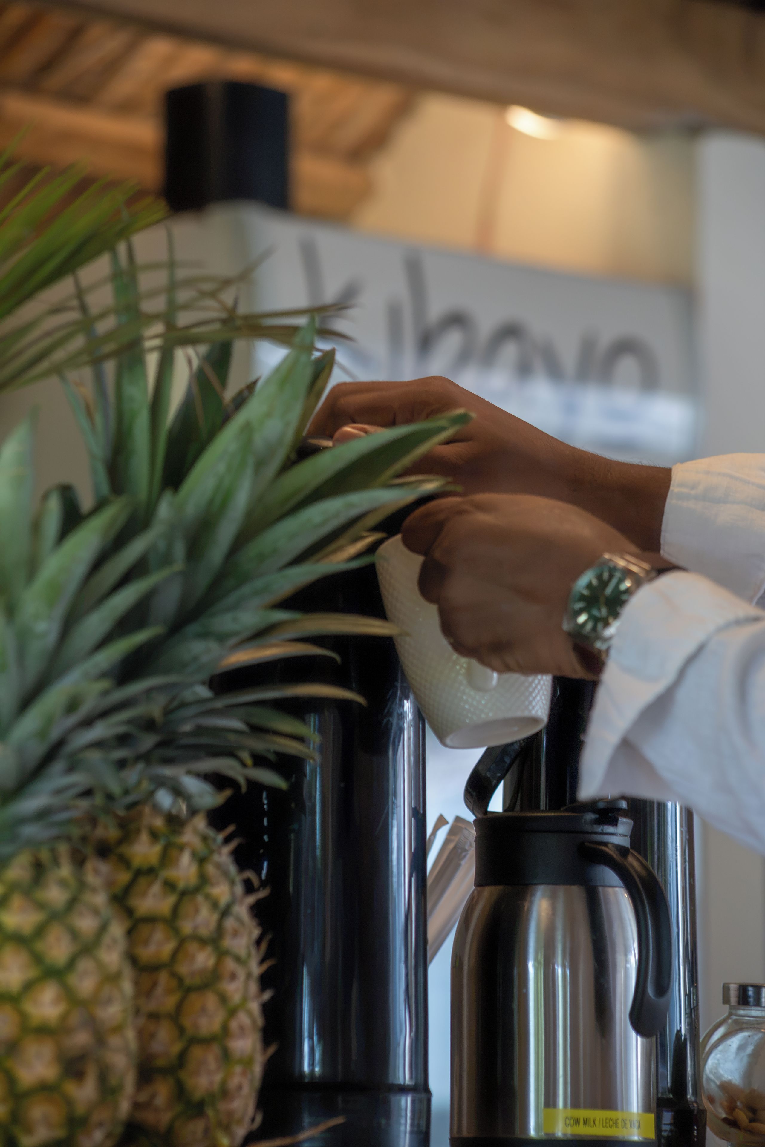A person operating a coffee machine with a pineapple on the counter.