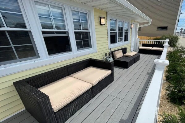 A covered porch with wicker furniture and a white railing.