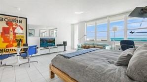 A modern bedroom with a large bed, a desk, a chair, a TV, and a view of the ocean. - Romantic-Stunning-Ocean view-Balcony-Panoramic-Amazing Sunrise-Miami-South-Beach (Miami Beach)