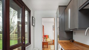 A narrow kitchen with a washing machine, a wooden countertop, and a view of a garden through a large window. - 4 bedroom accommodation in Blackdown Hills, near Culmstock (Blackdown Hills, near Culmstock)