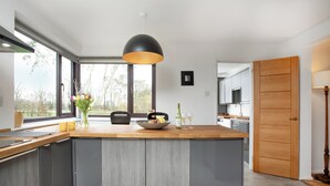 A modern kitchen with a large island, wooden countertops, and a black pendant light. - 4 bedroom accommodation in Blackdown Hills, near Culmstock (Blackdown Hills, near Culmstock)