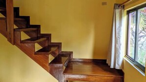 Eine Holztreppe führt zu einer Zwischenebene mit einem Fenster.