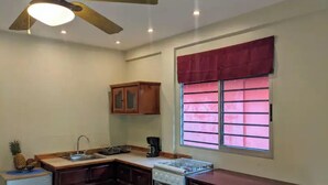 A compact kitchen with dark wooden cabinets, a built-in oven, a sink, and a ceiling fan. - Comfortable Casita, walking distance to the Beach (Puntarenas Province)