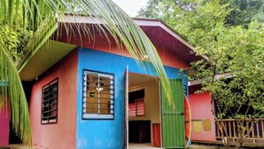 A colorful house with a blue and red exterior, a green door, and a window with bars. - Comfortable Casita, walking distance to the Beach (Puntarenas Province)