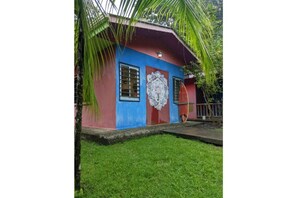 Un pequeño edificio colorido con fachada roja y azul, una puerta decorativa y un porche pequeño.