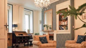 A living room with a chandelier, two sofas, a coffee table, a bookshelf, and a mirror. - LA Maison Bordeaux: Celebrating Lifes Pleasures, the French Way (Bordeaux)