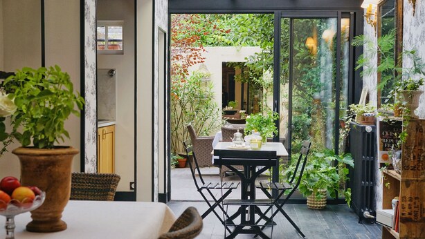 A dining area with a table and chairs, surrounded by potted plants and a view of the garden. - LA Maison Bordeaux: Celebrating Lifes Pleasures, the French Way (Bordeaux)