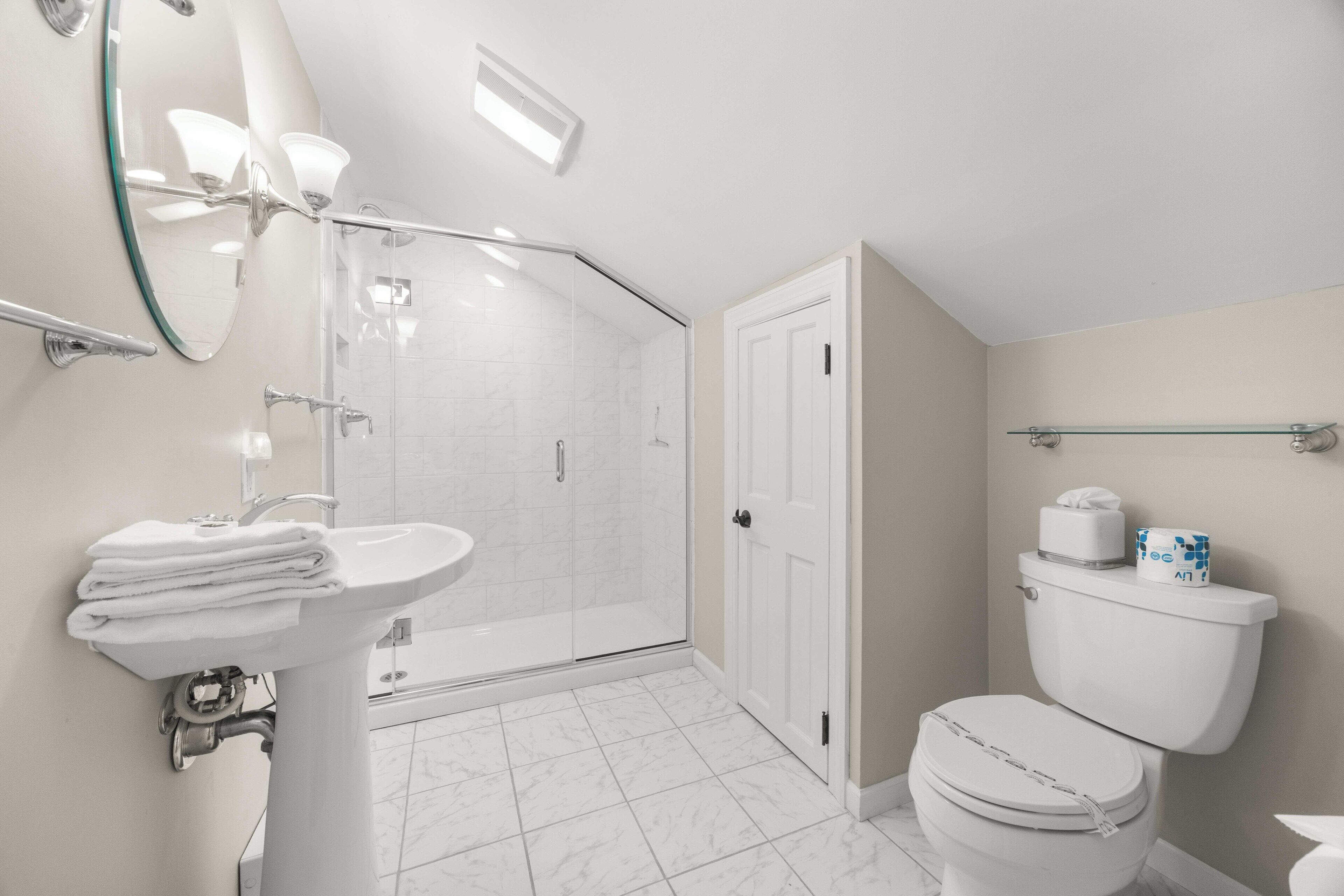 Une salle de bain moderne avec une douche à parois de verre, un lavabo sur colonne et des toilettes.