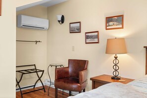 A room with a bed, a chair, a lamp, and wall-mounted pictures.