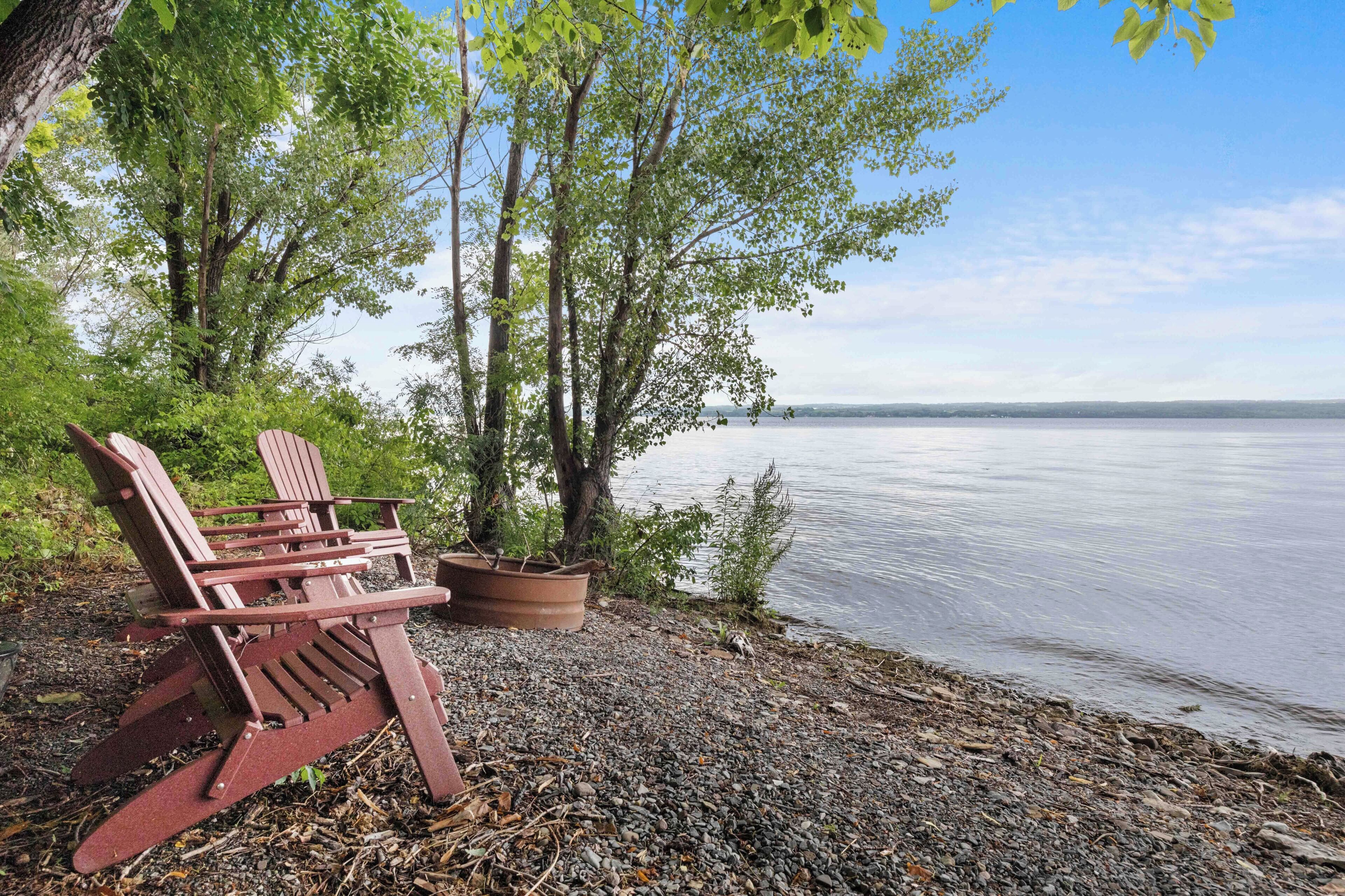 A lakeside setting with a wooden bench and a planter.