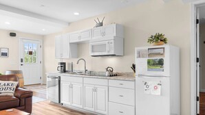 A modern kitchen with white cabinetry, a built-in microwave, and a refrigerator with a small window.