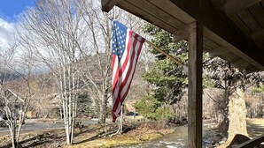 A wooden deck overlooking a river with an American flag.