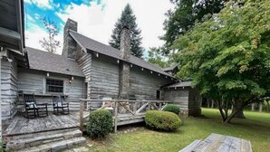A rustic wooden cabin with a porch, a picnic table, and a small garden area.