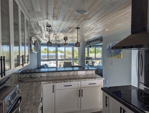 Una cocina moderna con armarios blancos, encimera negra y un amplio ventanal con vistas al exterior.