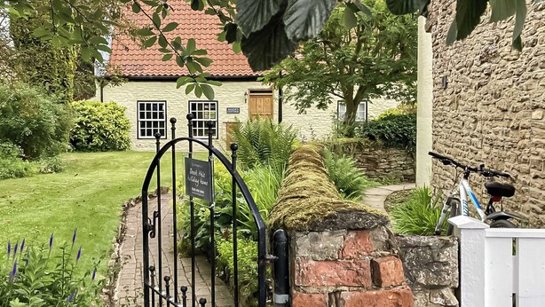 A traditional stone house with a brick wall, a metal gate, and a sign indicating a holiday home. - 3 bedroom accommodation in Hotham, near Beverley (Hotham, near Beverley)