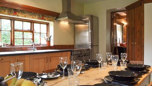 A kitchen with wooden cabinets, a stainless steel refrigerator, and a dining table set with plates and glasses. - 3 bedroom accommodation in Hotham, near Beverley (Hotham, near Beverley)