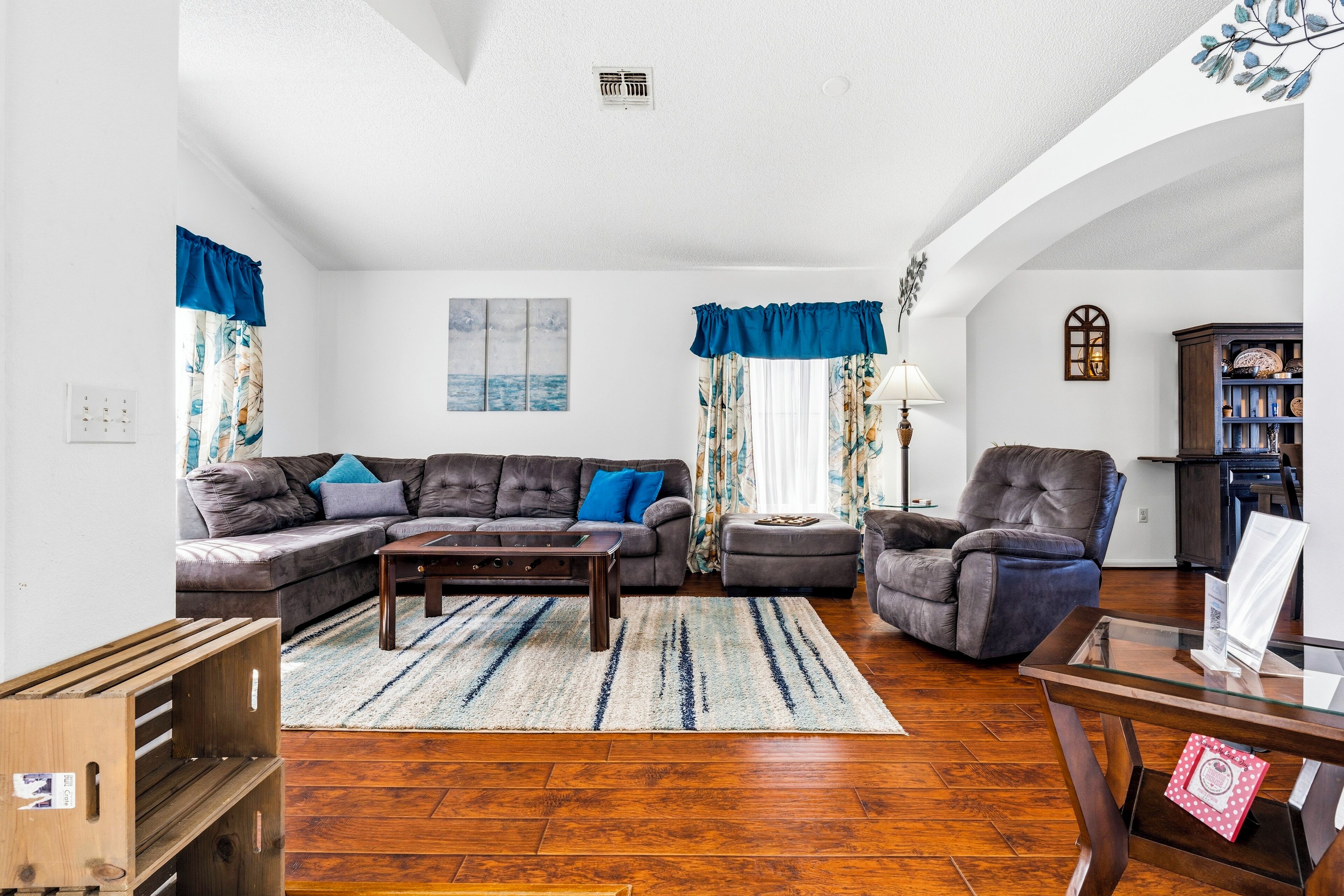 A living room with a sectional sofa, a coffee table, a glass table, and a fireplace.