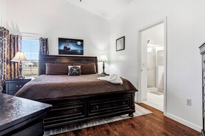 Une chambre à coucher avec un grand lit, une table de chevet, une lampe et un tableau représentant un navire accroché au mur.