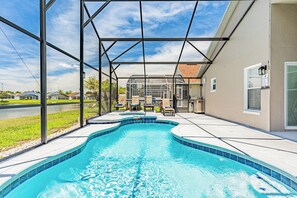 Une piscine avec un patio couvert, du mobilier d’extérieur et une vue sur le quartier.