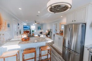 A spacious kitchen with a large island, stainless steel appliances, and a modern ceiling light fixture.