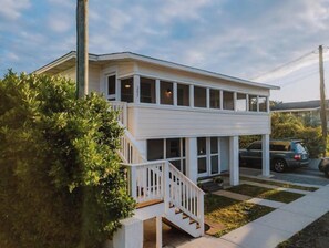 A two-story house with a white exterior, a front porch with a staircase, and a garage.