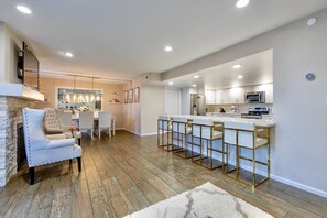 A modern kitchen with a bar area, a fireplace, and a dining area with a chandelier.