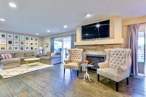 A spacious living room with a fireplace, two armchairs, a sofa, and a coffee table.