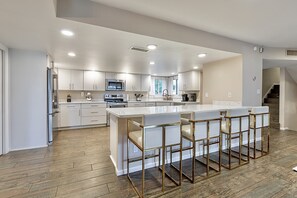 A modern kitchen with a central island, bar stools, and built-in appliances.