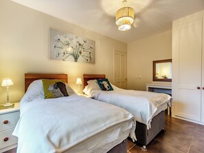 Ein Hotelzimmer mit zwei Betten, einem Nachttisch mit Lampe, einem Bild an der Wand, einem Kleiderschrank und einem Spiegel.