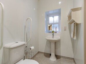 Ein modernes Badezimmer mit Toilette, Bidet, Waschbecken und einem Fenster.