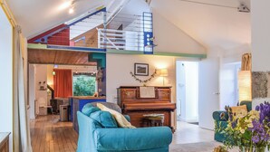 A spacious living room with a teal sofa, a piano, and a staircase leading to an upper level. - You’ll love the bright open space allowing for some real family fun. (Lothianburn, near Edinburgh)