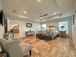 A spacious bedroom with a large bed, a desk, and a chair. - Spacious High Quality New Home - 1 Block to the Beach - 1 Pet Friendly (St. Augustine)