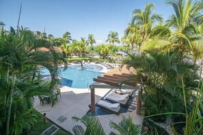 Un espace piscine avec des chaises longues et des palmiers.