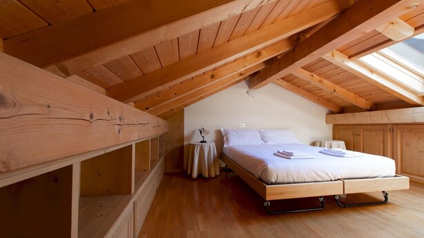 A cozy attic bedroom with a wooden bunk bed, a bedside table, and a nightstand. - Monte Solena 45C in Bormio (Bormio)