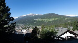 A mountain village with traditional houses, a clear sky, and snow-capped peaks in the background. - Monte Solena 45C in Bormio (Bormio)